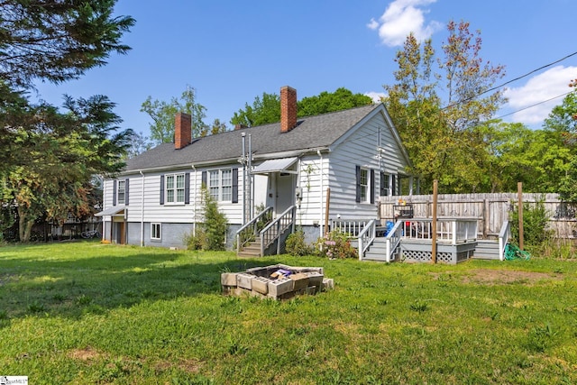 back of property featuring a yard, fence, a wooden deck, and a chimney