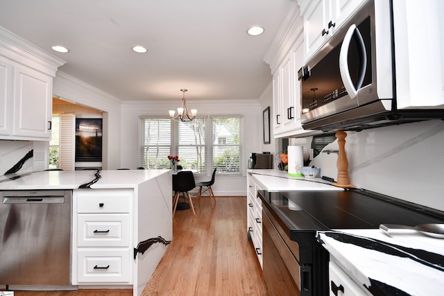 kitchen with light countertops, white cabinets, appliances with stainless steel finishes, and a chandelier