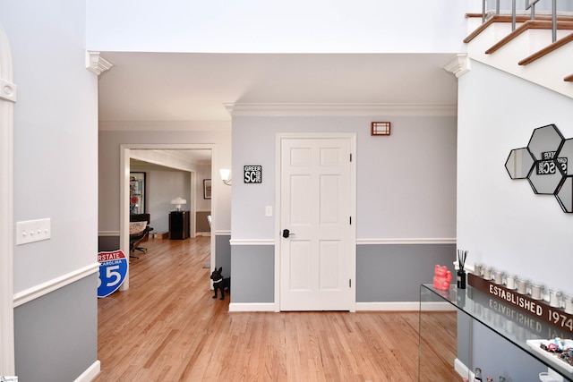 foyer featuring ornamental molding, baseboards, light wood finished floors, and stairs