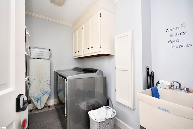 clothes washing area featuring ornamental molding, a sink, baseboards, cabinet space, and washer and clothes dryer