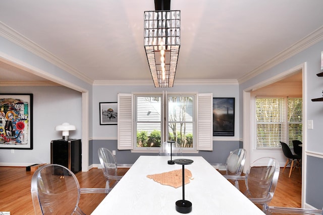 dining space with wood finished floors, ornamental molding, and plenty of natural light