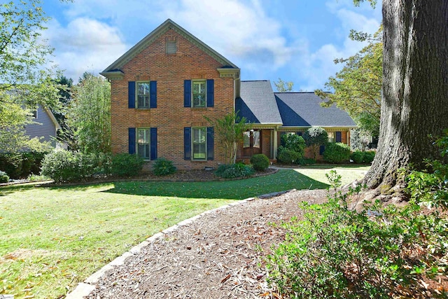 traditional-style house featuring a front lawn and brick siding