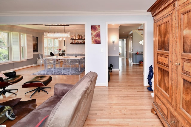 living area featuring ornamental molding, baseboards, an inviting chandelier, and light wood-style floors