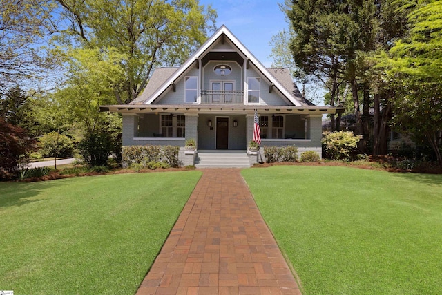 view of front facade with a porch, a front yard, and brick siding