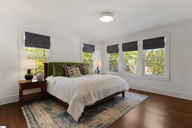 bedroom with crown molding, baseboards, dark wood-style floors, and visible vents