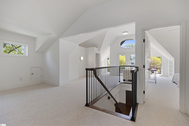 hallway with baseboards, vaulted ceiling, carpet, and an upstairs landing
