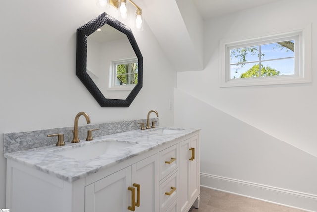 bathroom with double vanity, a sink, and baseboards