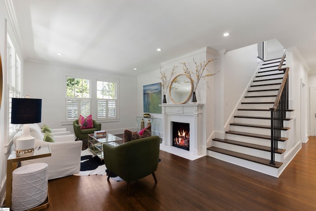 living area featuring a fireplace with flush hearth, crown molding, wood finished floors, and stairway