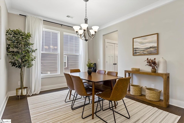 dining space featuring visible vents, baseboards, a notable chandelier, and wood finished floors