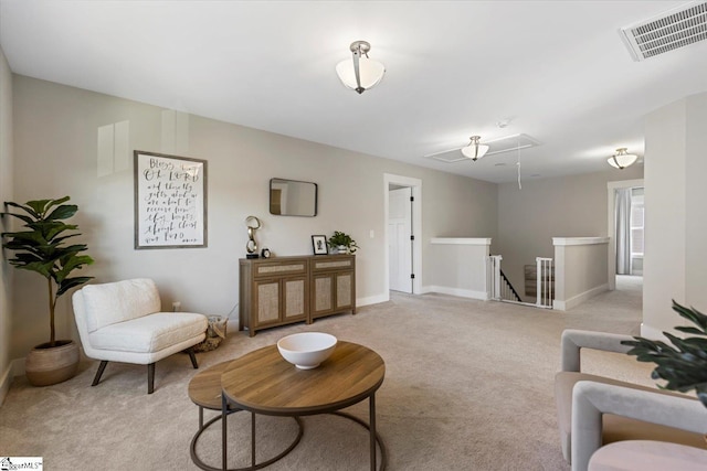 living area with visible vents, baseboards, attic access, and light colored carpet