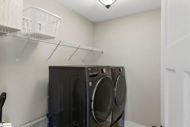 clothes washing area featuring washer and dryer, laundry area, and baseboards