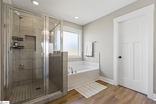 full bathroom featuring a garden tub, a shower stall, recessed lighting, wood finished floors, and baseboards