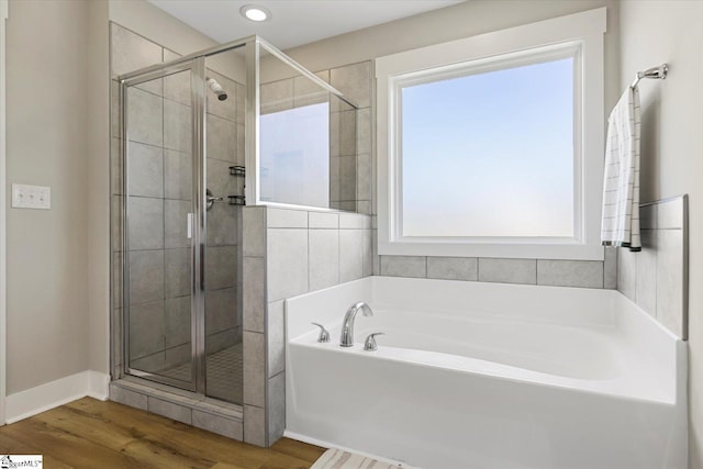 full bath with a shower stall, wood finished floors, baseboards, and a garden tub