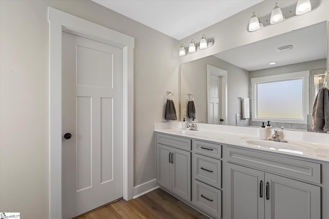 bathroom with wood finished floors, double vanity, a sink, and visible vents
