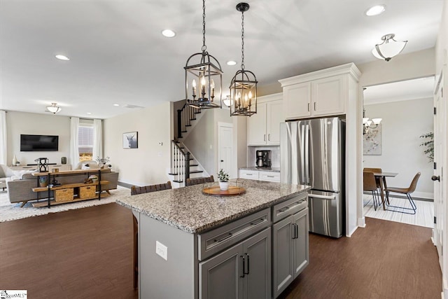 kitchen with white cabinets, a notable chandelier, open floor plan, freestanding refrigerator, and dark wood-type flooring