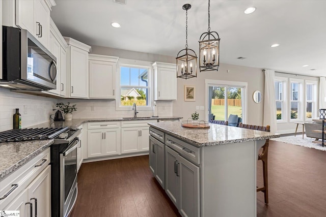 kitchen with a kitchen island, dark wood-type flooring, a breakfast bar area, appliances with stainless steel finishes, and a sink