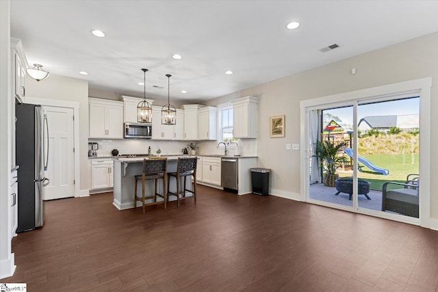 kitchen with stainless steel appliances, a wealth of natural light, visible vents, and a breakfast bar