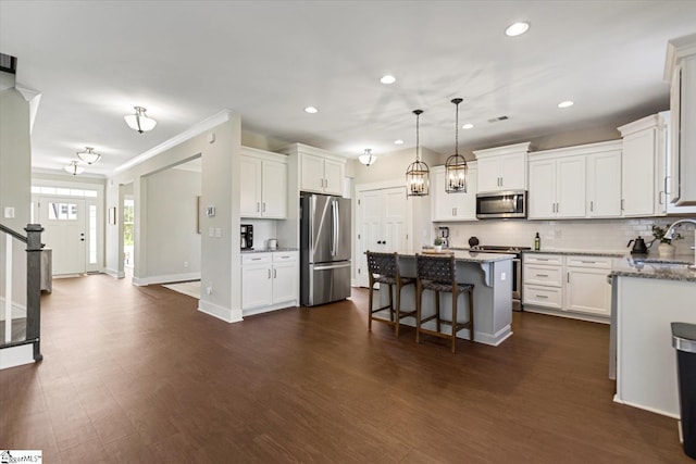 kitchen featuring appliances with stainless steel finishes, a kitchen breakfast bar, white cabinets, dark wood finished floors, and decorative backsplash