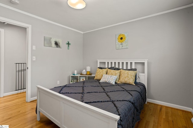 bedroom featuring light wood-style flooring, crown molding, and baseboards