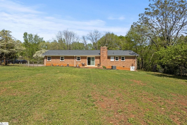 rear view of property featuring a yard, a chimney, fence, central air condition unit, and brick siding