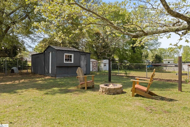 view of yard featuring a storage shed, an outdoor fire pit, fence, and an outbuilding