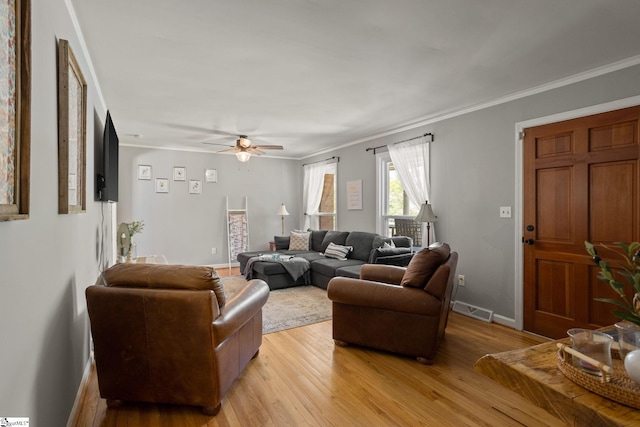 living area featuring visible vents, baseboards, a ceiling fan, light wood-style floors, and crown molding
