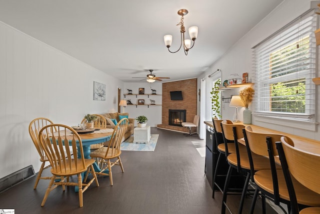 dining area with ceiling fan with notable chandelier and a fireplace