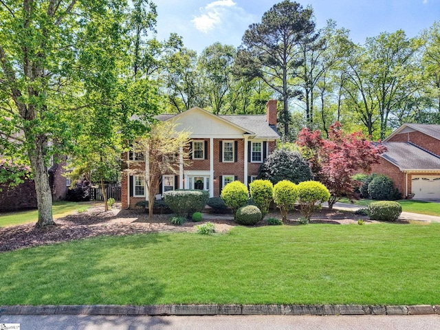 greek revival house featuring a chimney, a front lawn, and brick siding