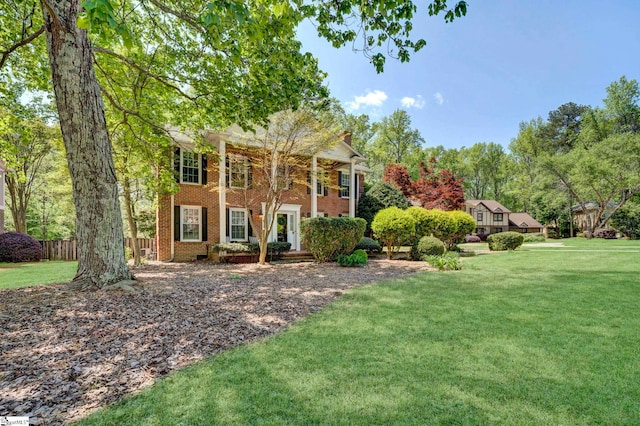 view of front of house featuring brick siding, a front lawn, and fence