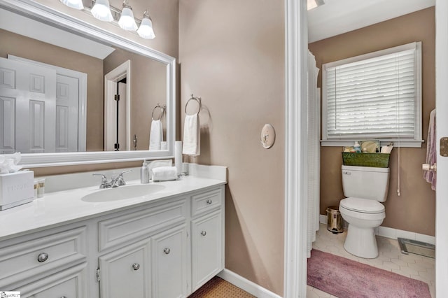 bathroom featuring tile patterned flooring, vanity, baseboards, and toilet