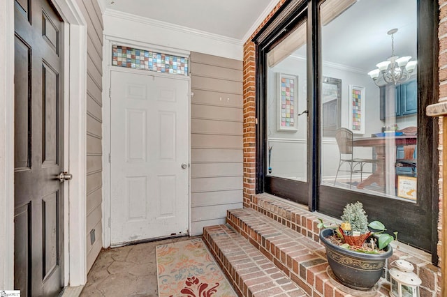 foyer entrance with wooden walls, ornamental molding, and an inviting chandelier
