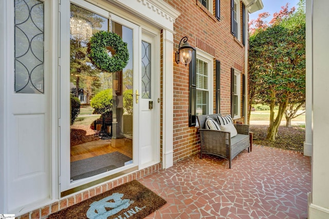 doorway to property featuring covered porch and brick siding