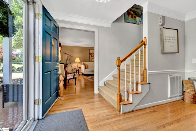 foyer featuring light wood-style flooring, ornamental molding, visible vents, stairs, and baseboards