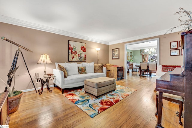 living area featuring light wood finished floors, a notable chandelier, baseboards, and ornamental molding