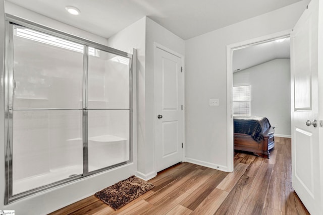 bathroom with baseboards, a shower stall, and wood finished floors