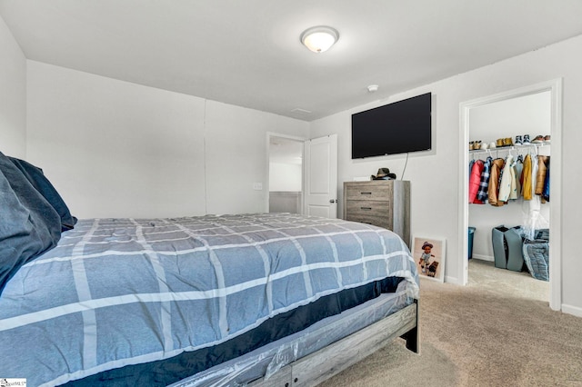 bedroom featuring a walk in closet, a closet, baseboards, and carpet