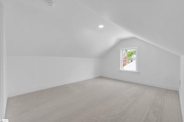 additional living space featuring light colored carpet, baseboards, and vaulted ceiling