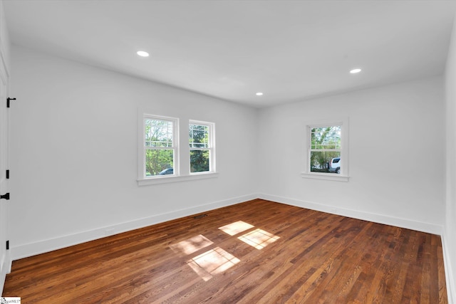 spare room featuring baseboards, wood finished floors, and a healthy amount of sunlight