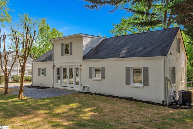 rear view of house featuring french doors, a shingled roof, a yard, and central AC