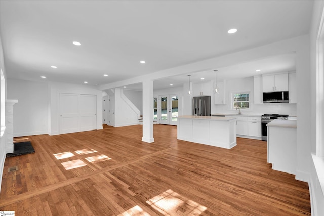 kitchen with light wood-style flooring, a center island, light countertops, visible vents, and stainless steel appliances