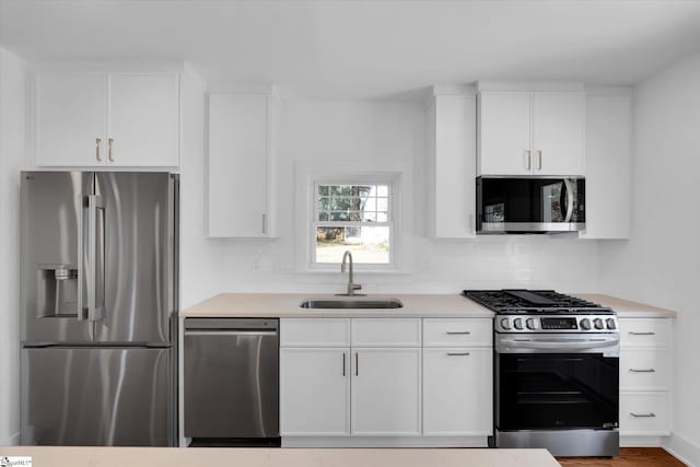 kitchen with stainless steel appliances, light countertops, white cabinetry, and a sink