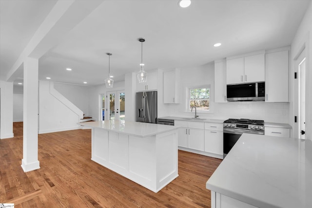 kitchen featuring a center island, appliances with stainless steel finishes, light wood finished floors, and a sink