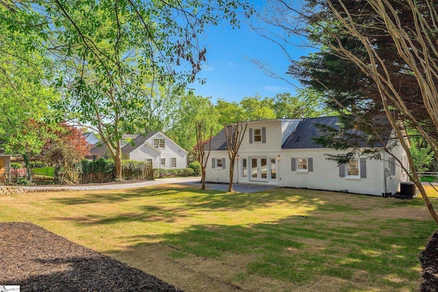 rear view of house featuring a patio, stucco siding, french doors, central AC, and a lawn