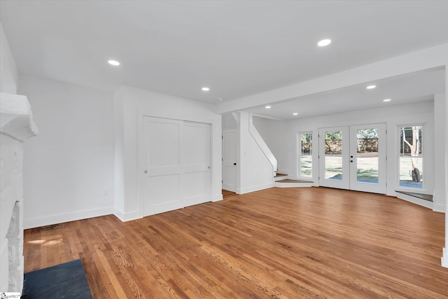 unfurnished living room featuring baseboards, light wood finished floors, recessed lighting, and stairs