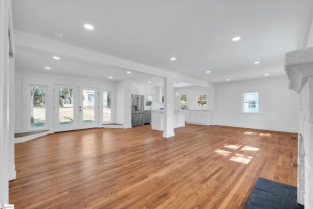 unfurnished living room with french doors, baseboards, recessed lighting, and light wood-style floors