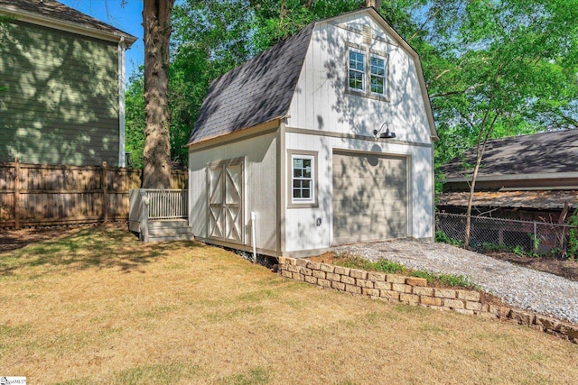 view of outdoor structure with an outbuilding, fence, and driveway