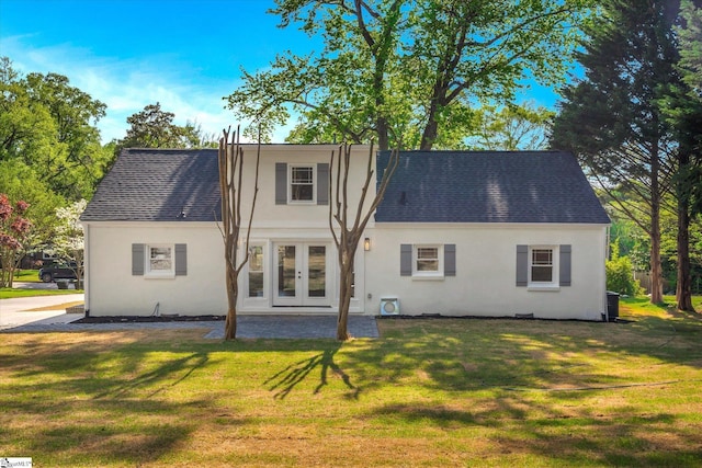 rear view of property with a yard, french doors, a shingled roof, and stucco siding
