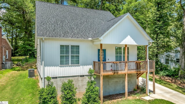 view of front of house featuring a front yard, a shingled roof, a wooden deck, and central air condition unit
