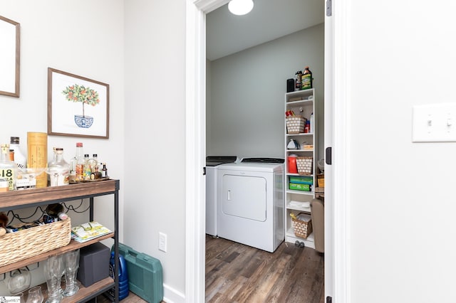 clothes washing area with washer and clothes dryer, laundry area, a dry bar, and wood finished floors