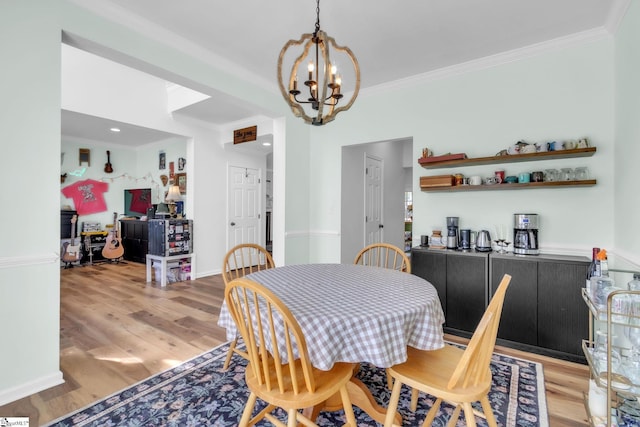 dining space with a chandelier, light wood-style floors, crown molding, and baseboards